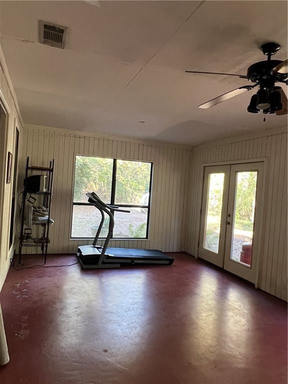 workout room with french doors, plenty of natural light, wood walls, and ceiling fan