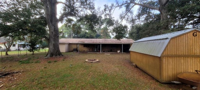 rear view of house with a fire pit and a shed