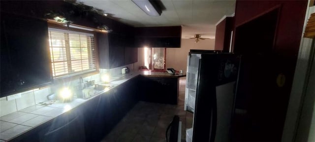 kitchen featuring kitchen peninsula, backsplash, ceiling fan, sink, and tile countertops