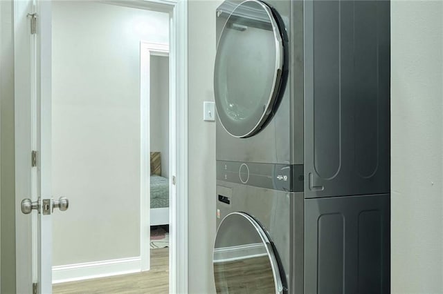 laundry room featuring stacked washer and dryer and light wood-type flooring