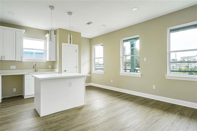 kitchen featuring a healthy amount of sunlight, decorative light fixtures, a center island, and white cabinets