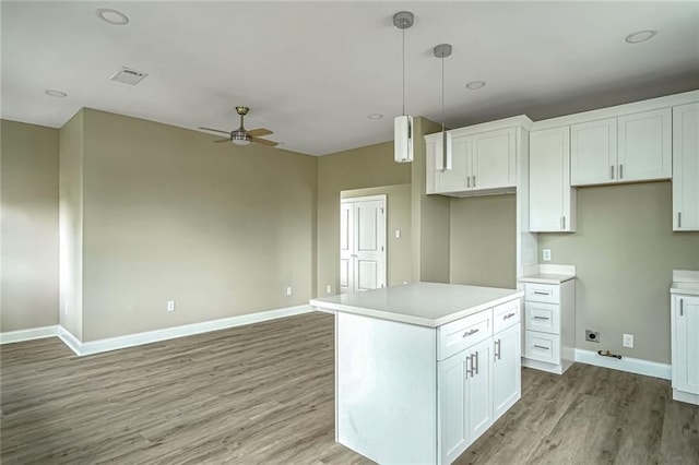 kitchen featuring decorative light fixtures, a kitchen island, ceiling fan, light hardwood / wood-style floors, and white cabinets