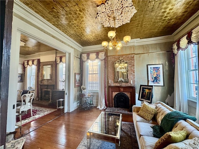 living area with crown molding, hardwood / wood-style flooring, a chandelier, and a large fireplace