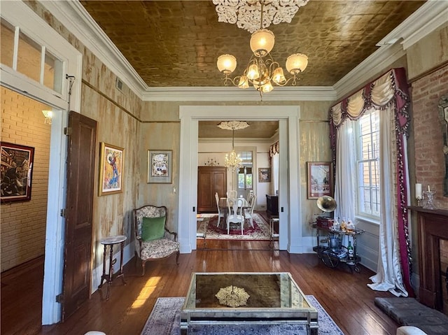 foyer with a notable chandelier, brick wall, and crown molding