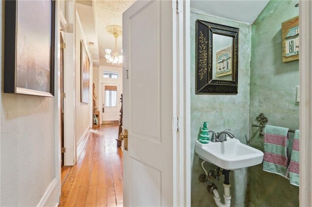 bathroom with a notable chandelier, baseboards, and hardwood / wood-style flooring