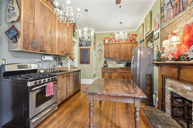 kitchen with crown molding, brown cabinets, wood finished floors, stainless steel appliances, and a sink