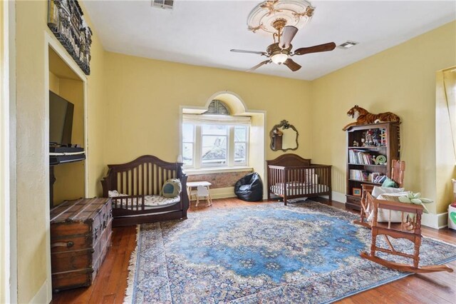 living area with a ceiling fan, visible vents, wood finished floors, and baseboards