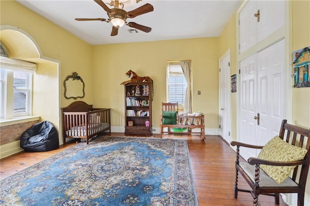 living area with visible vents, baseboards, hardwood / wood-style floors, and a ceiling fan