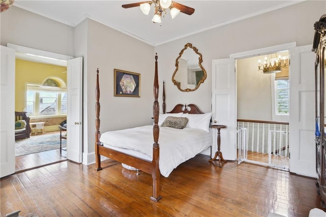 bedroom featuring ceiling fan with notable chandelier, hardwood / wood-style flooring, and crown molding