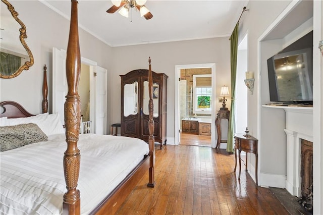 bedroom with a ceiling fan, dark wood-style floors, baseboards, ensuite bathroom, and crown molding