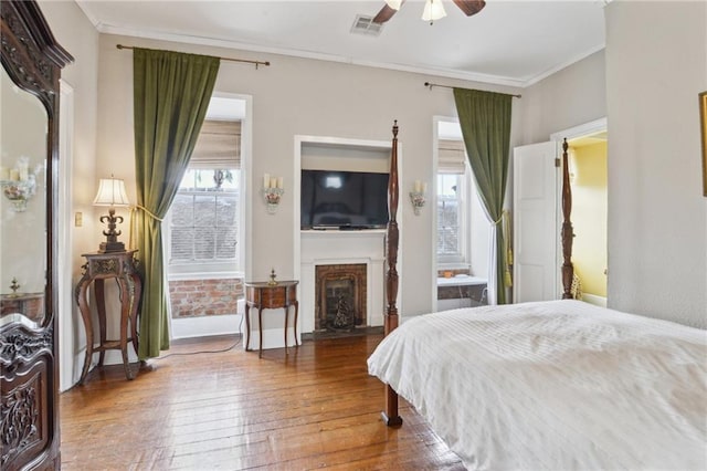 bedroom featuring visible vents, multiple windows, ornamental molding, and hardwood / wood-style flooring