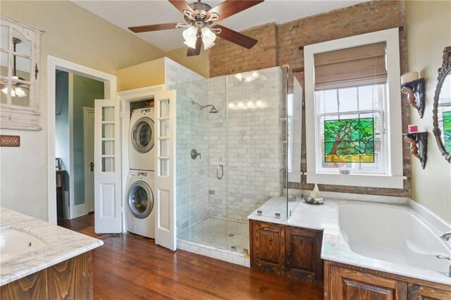 full bath with stacked washer / dryer, a shower stall, wood finished floors, a bath, and vanity