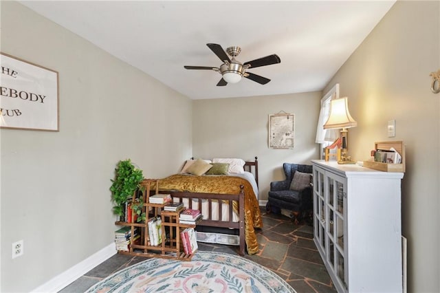 bedroom with stone finish floor, a ceiling fan, and baseboards