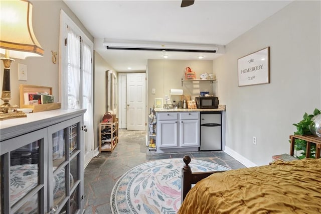 bedroom featuring refrigerator and baseboards