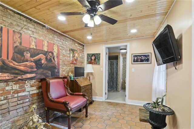 sitting room featuring baseboards, wood ceiling, and brick wall