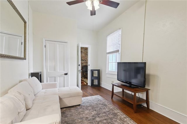 living area with a ceiling fan, wood finished floors, and baseboards