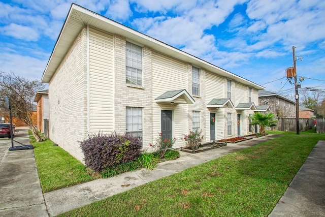 townhome / multi-family property featuring a front lawn