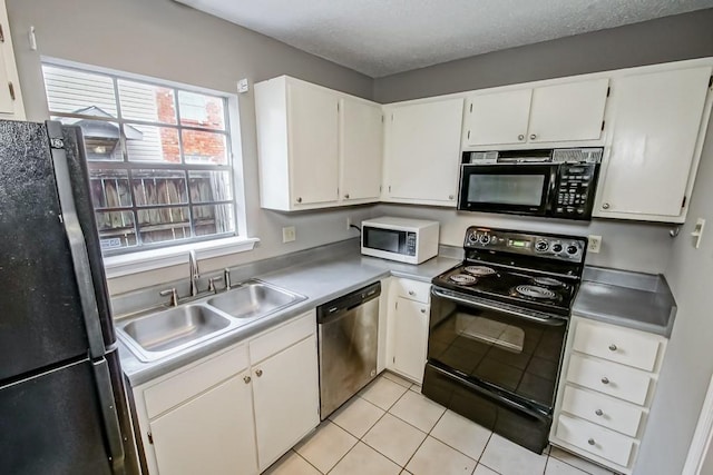 kitchen featuring a textured ceiling, sink, black appliances, light tile patterned floors, and white cabinets