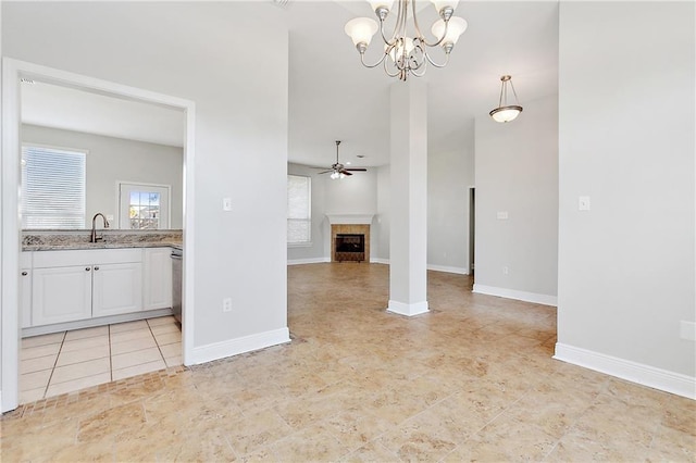 unfurnished living room featuring a tile fireplace, light tile patterned floors, ceiling fan with notable chandelier, and sink