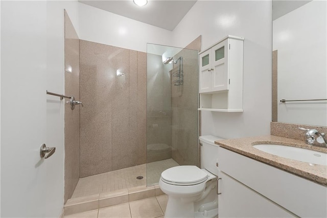 bathroom with tile patterned flooring, vanity, a tile shower, and toilet