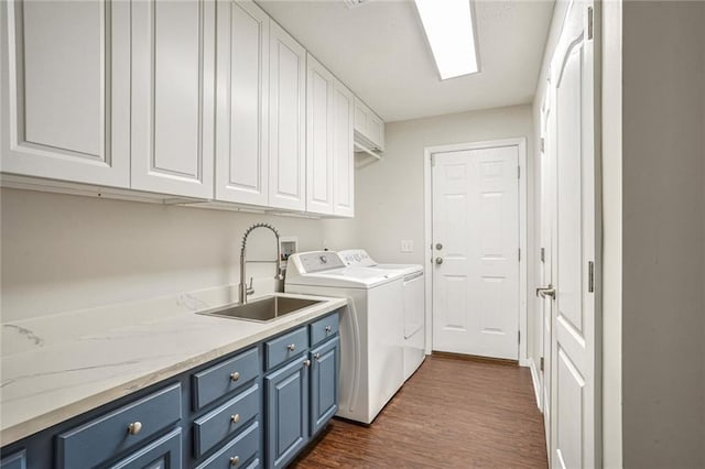 clothes washing area featuring washer and clothes dryer, dark hardwood / wood-style floors, cabinets, and sink