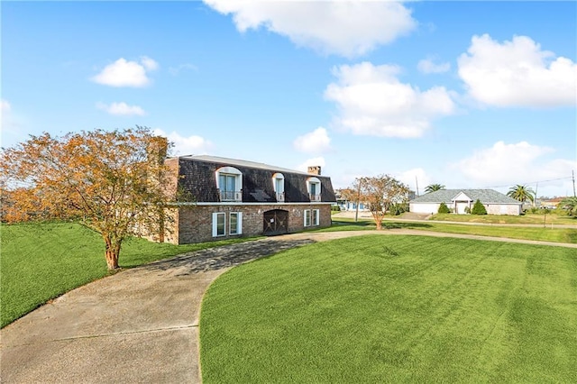 front of property with a front yard and mansard roof