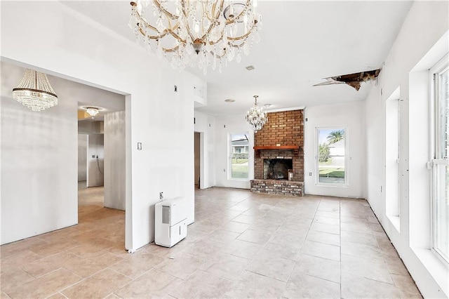 unfurnished living room featuring light tile patterned floors, a fireplace, a chandelier, and a wealth of natural light