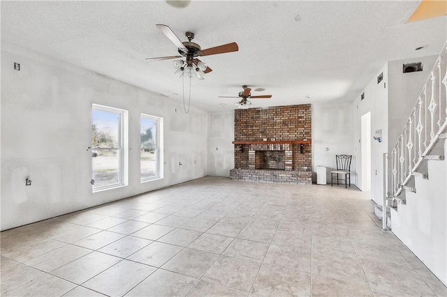 unfurnished living room with a fireplace, stairway, a textured ceiling, and light tile patterned floors