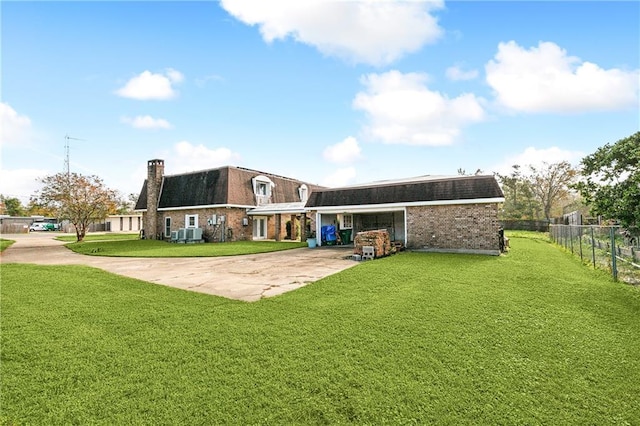 rear view of house featuring driveway, a lawn, fence, and mansard roof