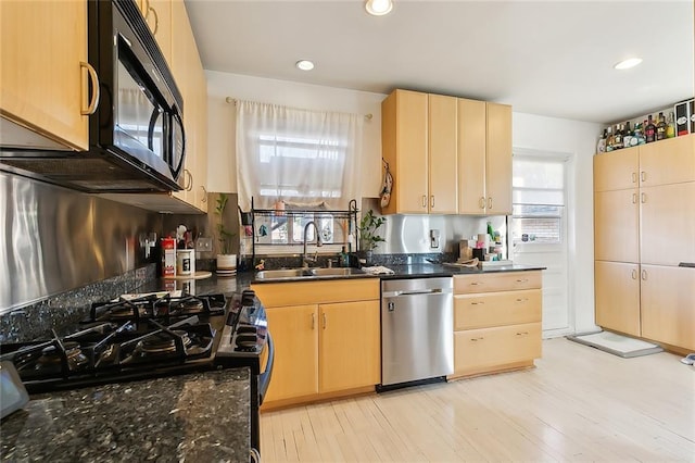 kitchen featuring dark stone counters, black appliances, sink, light wood-type flooring, and light brown cabinetry