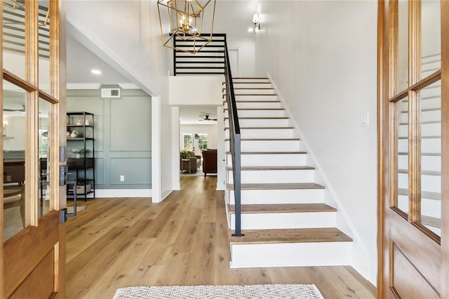 foyer with a notable chandelier, light wood-type flooring, and crown molding