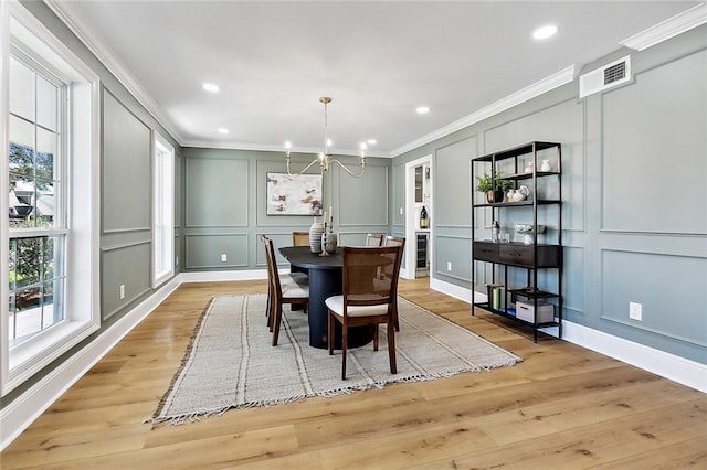 dining area featuring an inviting chandelier, light hardwood / wood-style floors, and ornamental molding