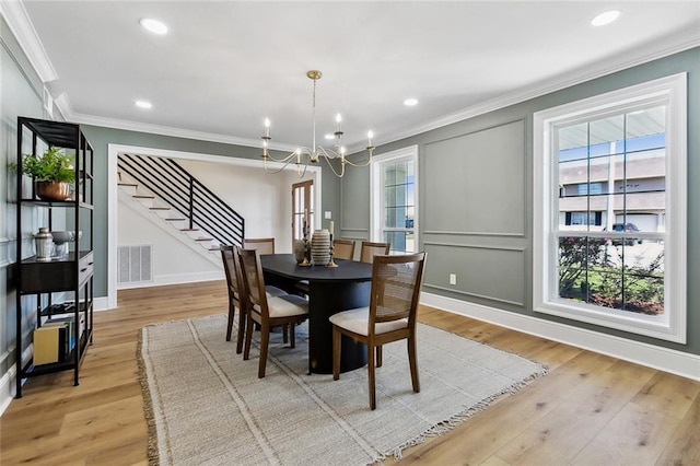 dining room featuring a chandelier, light hardwood / wood-style floors, and crown molding