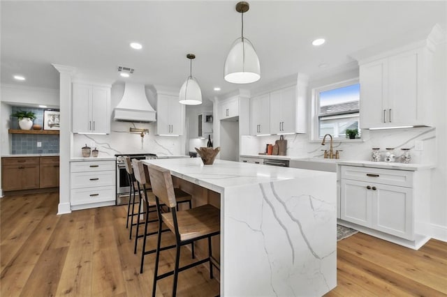 kitchen featuring a center island, white cabinets, high end stainless steel range oven, and custom exhaust hood