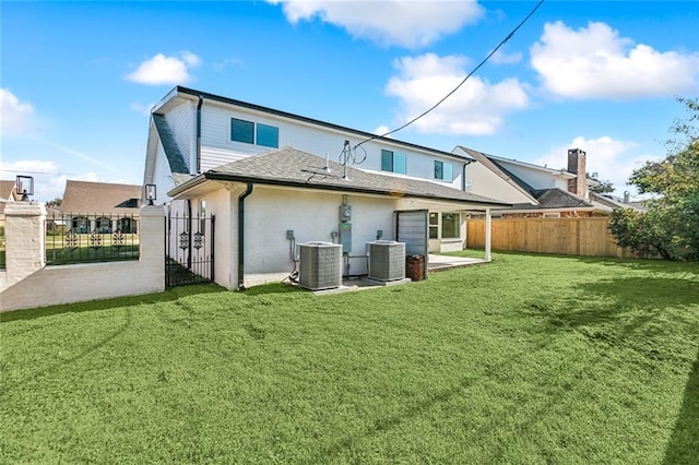 rear view of property featuring central air condition unit and a lawn