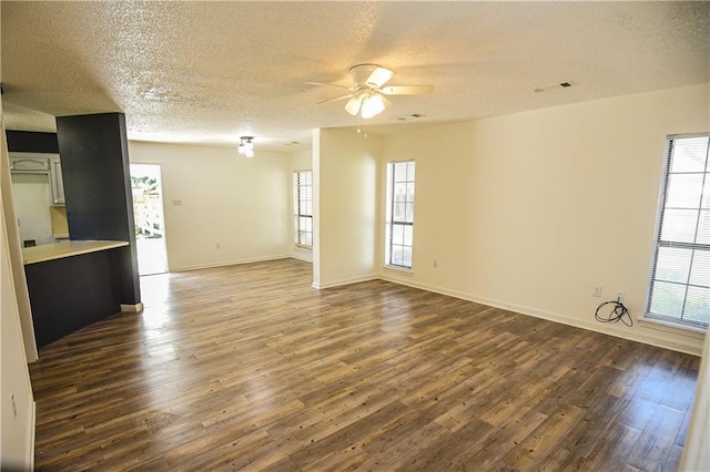 unfurnished living room featuring dark hardwood / wood-style floors, ceiling fan, and a textured ceiling