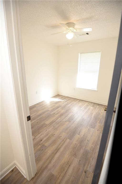 empty room with ceiling fan, a textured ceiling, and hardwood / wood-style flooring