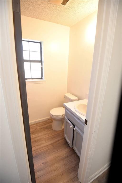 bathroom featuring toilet, vanity, a textured ceiling, and hardwood / wood-style flooring