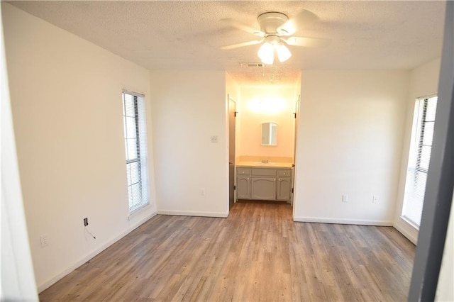 spare room with plenty of natural light, ceiling fan, a textured ceiling, and light hardwood / wood-style flooring