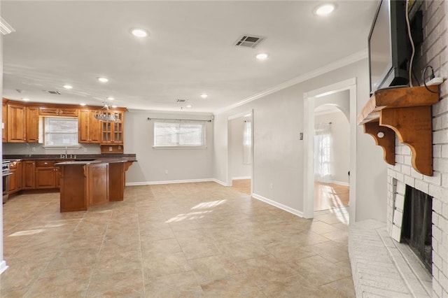 kitchen featuring a kitchen bar, ornamental molding, sink, a fireplace, and a center island