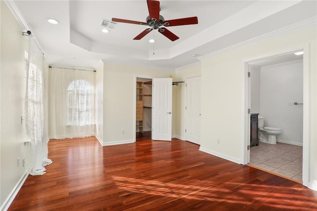 unfurnished bedroom with hardwood / wood-style flooring, ceiling fan, a raised ceiling, and connected bathroom