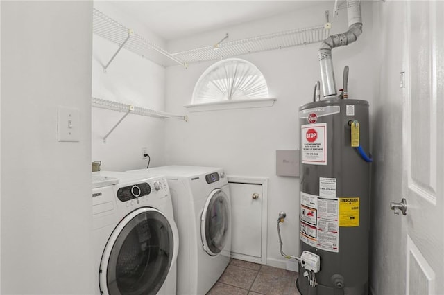 washroom with washer and clothes dryer, light tile patterned flooring, and gas water heater