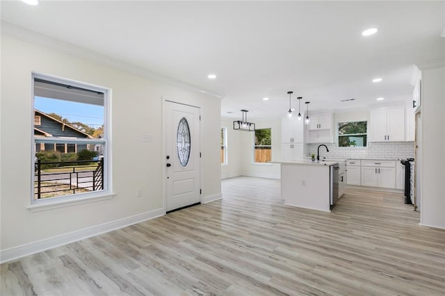 kitchen featuring white cabinetry, a center island with sink, a healthy amount of sunlight, and light wood-type flooring