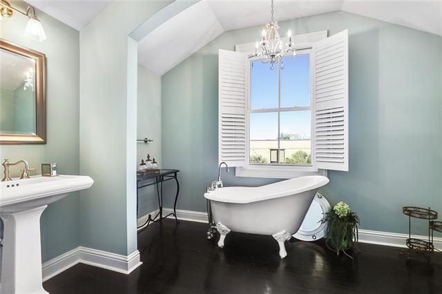 bathroom featuring hardwood / wood-style floors, a bathtub, an inviting chandelier, sink, and vaulted ceiling