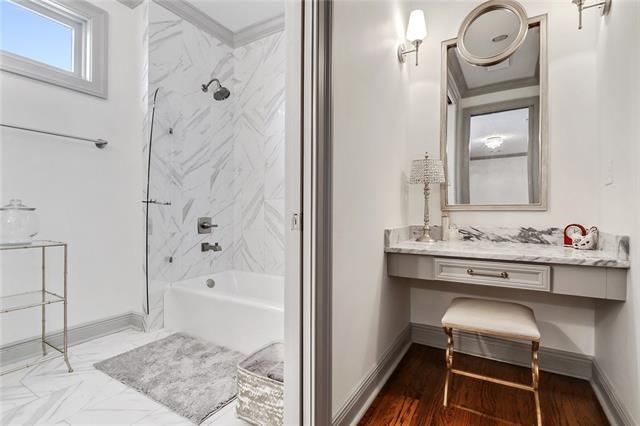 bathroom featuring vanity, tiled shower / bath combo, hardwood / wood-style flooring, and ornamental molding