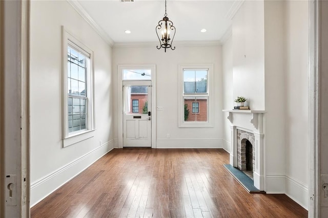 foyer entrance featuring plenty of natural light, dark hardwood / wood-style flooring, crown molding, and a chandelier