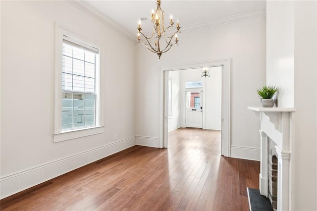 unfurnished dining area featuring crown molding, a high end fireplace, wood-type flooring, and an inviting chandelier