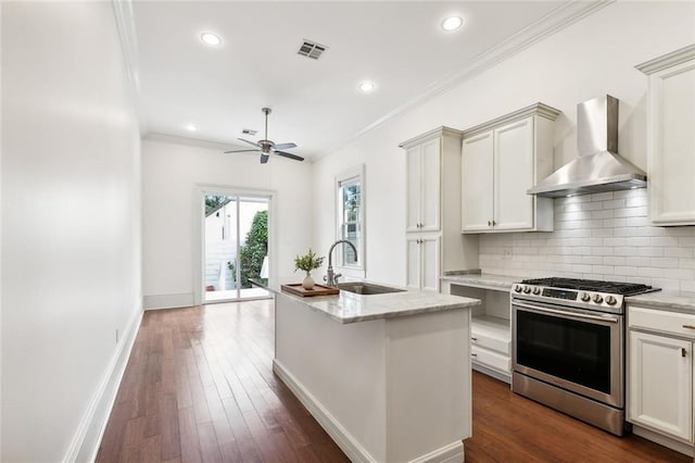 kitchen featuring light stone countertops, stainless steel gas range oven, a kitchen island with sink, dark wood-type flooring, and wall chimney range hood