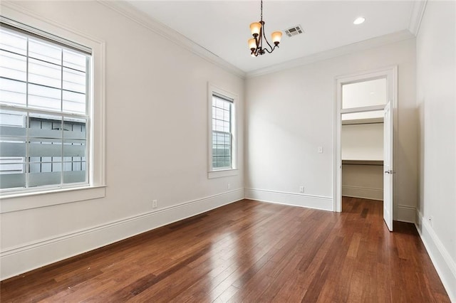 empty room with ornamental molding, dark wood-type flooring, and an inviting chandelier