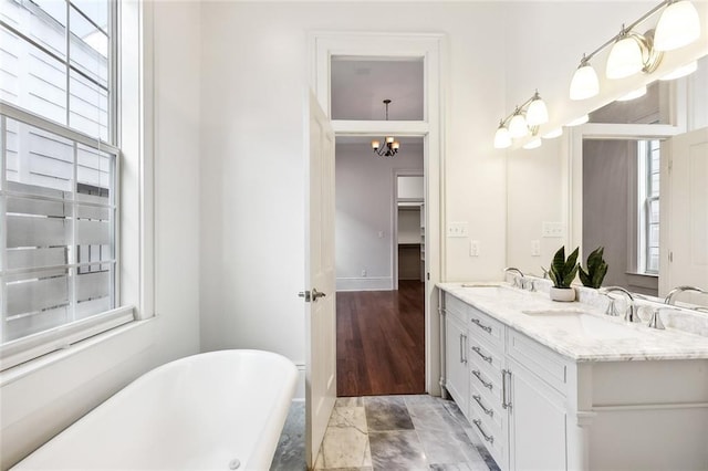 bathroom with a tub, vanity, a healthy amount of sunlight, and a notable chandelier